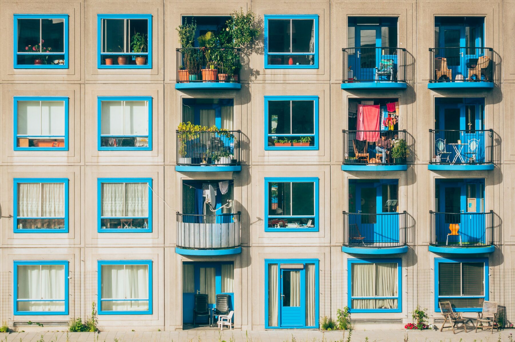 beige facade building with baby blue window trims and balconies with plants-types of liens article