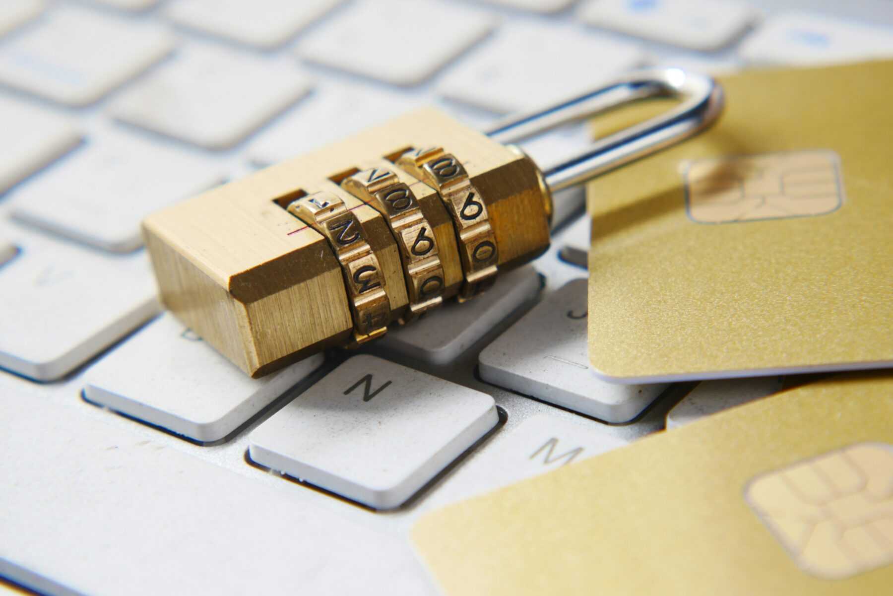 cybersecurity in real estate a golden, numerical lock placed on a white laptop keyboard along golden credit cards