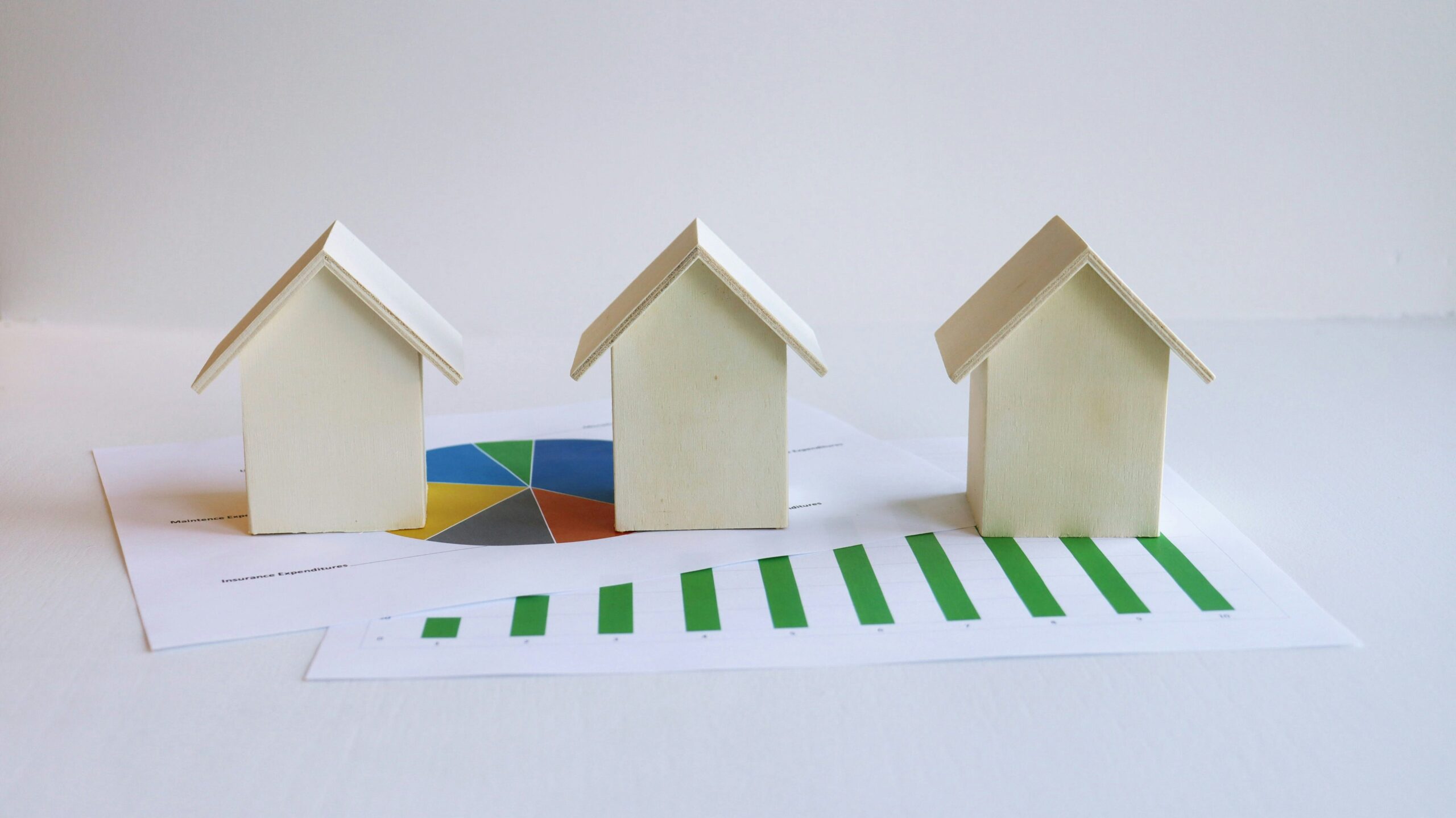 buyer's agent commission- three white model houses on top of papers with colorful charts